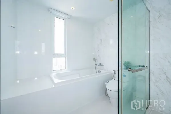 คอนโด ให้เช่าในWatthana, Bangkok - ห้องน้ำโทนขาว มีอ่างอาบน้ำ หน้าต่างสูง และตู้ shower กระจก