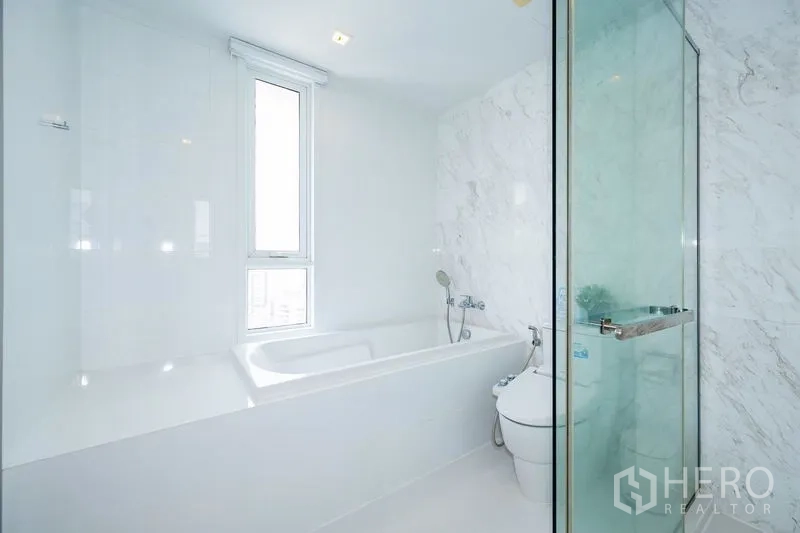 คอนโด ให้เช่าในWatthana, Bangkok - ห้องน้ำโทนขาว มีอ่างอาบน้ำ หน้าต่างสูง และตู้ shower กระจก