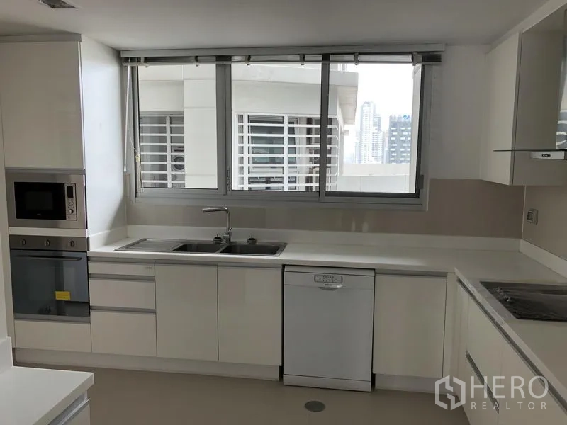 房间 出租在Watthana, Bangkok - 明亮的白色现代厨房，配大窗、嵌入式烤箱与微波炉、双水槽、洗碗机与城市景观。