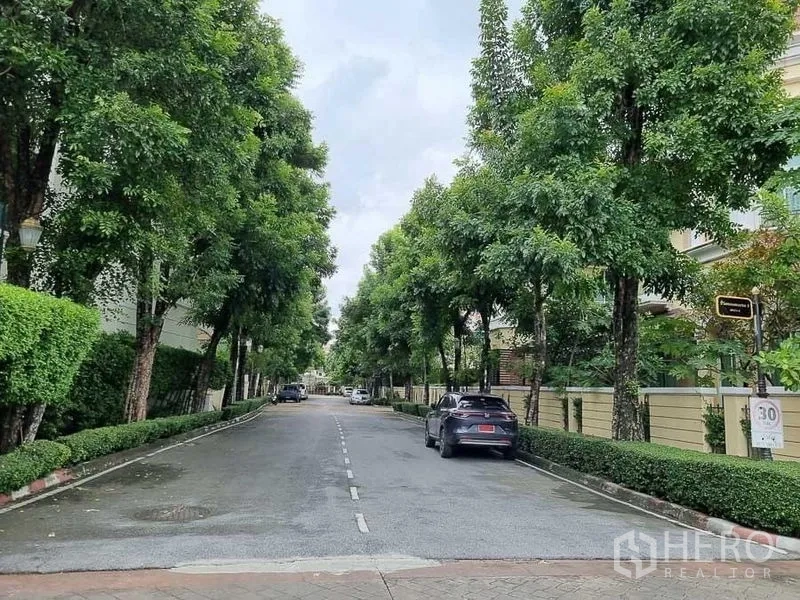 Detached House for rent in Yan Nawa, Bangkok - Tree-lined private estate road with hedges, parked cars and a speed-limit sign.
