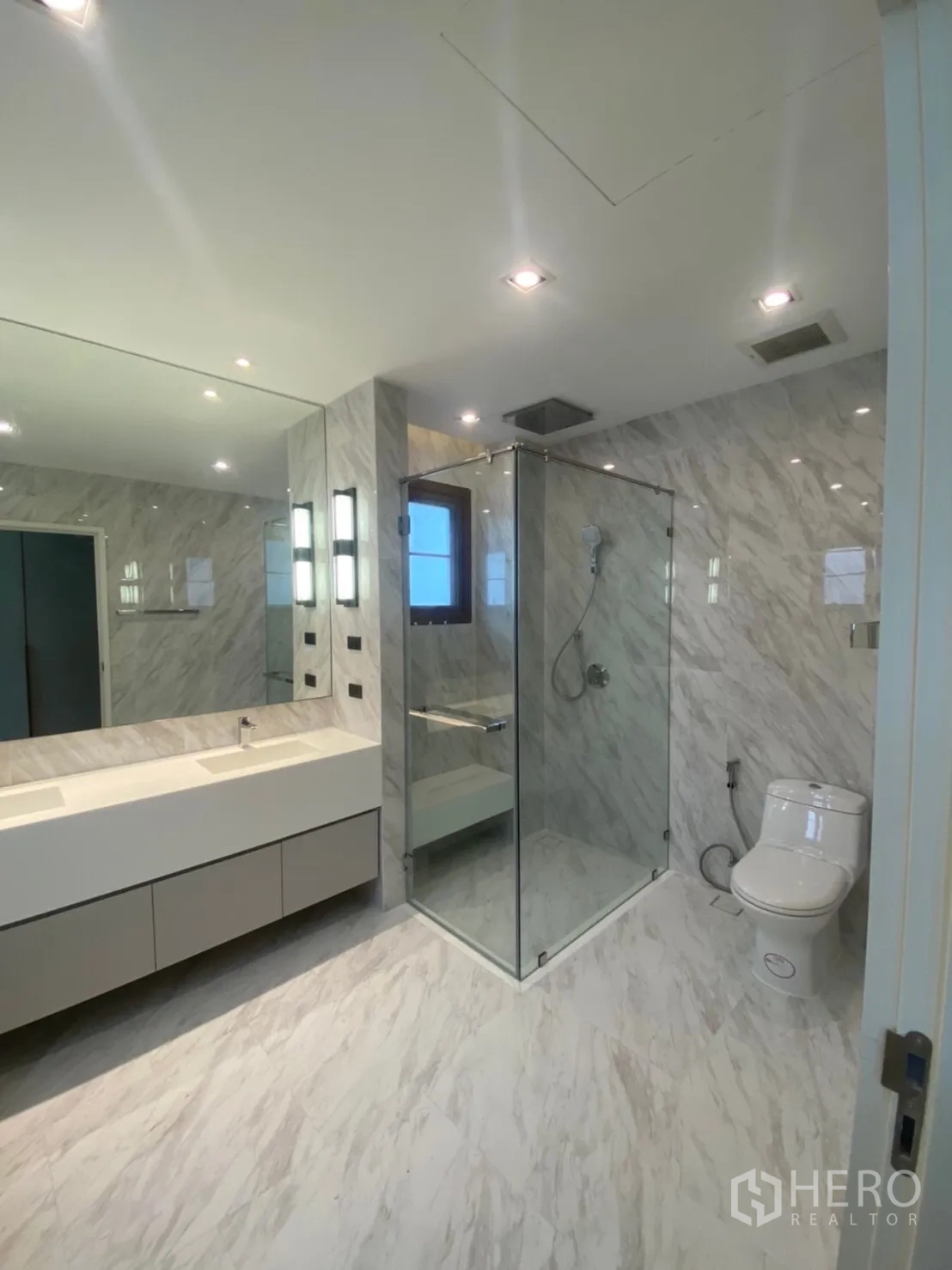 Detached House for rent in Bang Phli, Samut Prakan - Marble-clad bathroom with glass shower, double vanity and toilet under recessed lights.