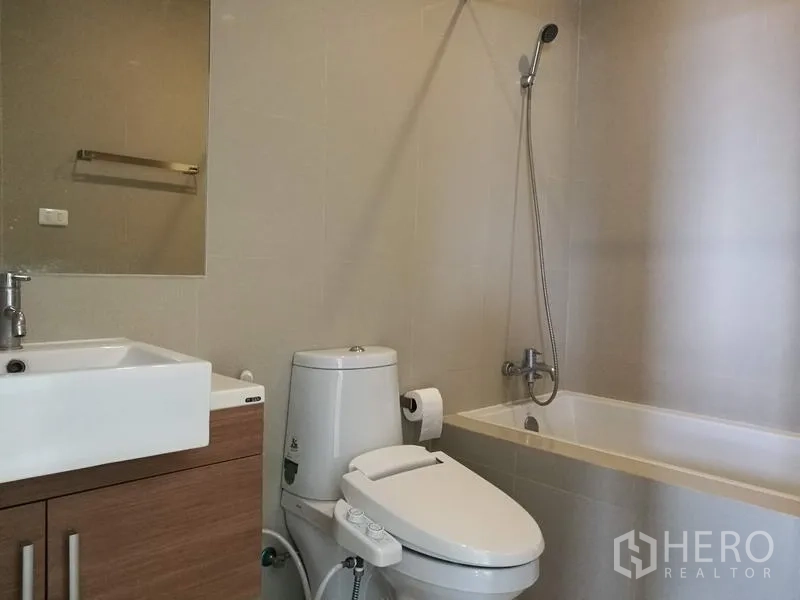 Condominium for rent in Watthana, Bangkok - Modern bathroom with vanity, toilet and bathtub with shower.