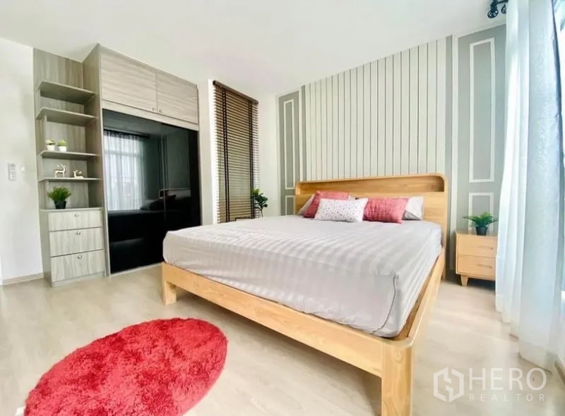 Townhouse for rent in Prawet, Bangkok - Master bedroom with built-in wardrobe, floor-to-ceiling windows and accent wall.