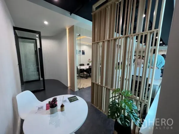 Office Space for rent - Reception nook with round table, wood slat divider and greenery beside meeting rooms.