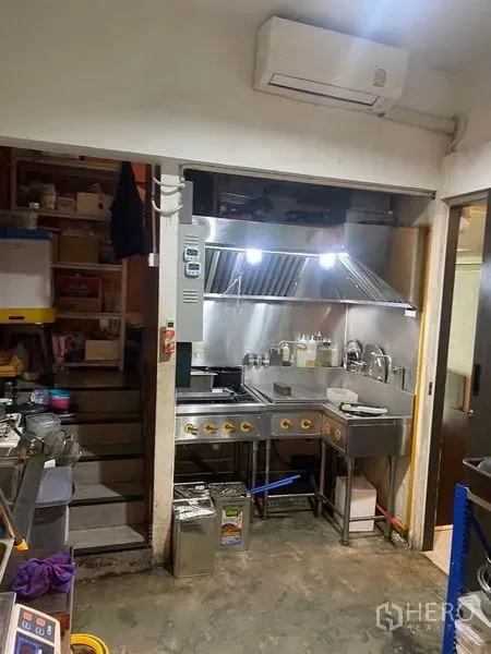 Shophouse for rent - Compact commercial kitchen with stainless stove, extractor hood, and sink ready for food prep.