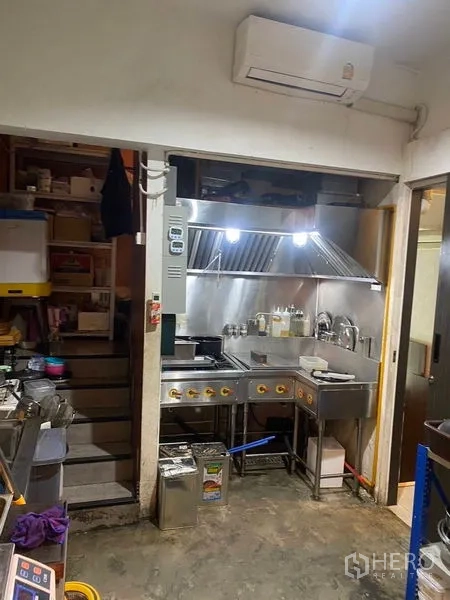 Shophouse for rent - Compact commercial kitchen with stainless stove, extractor hood, and sink ready for food prep.