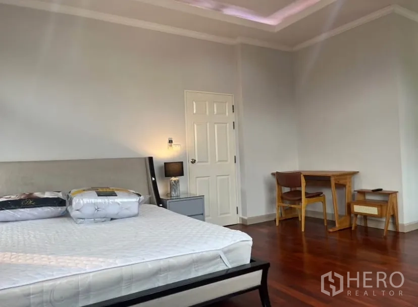 Detached House for rent or sale in Lat Phrao, Bangkok - Large master bedroom with tray ceiling and a study desk.