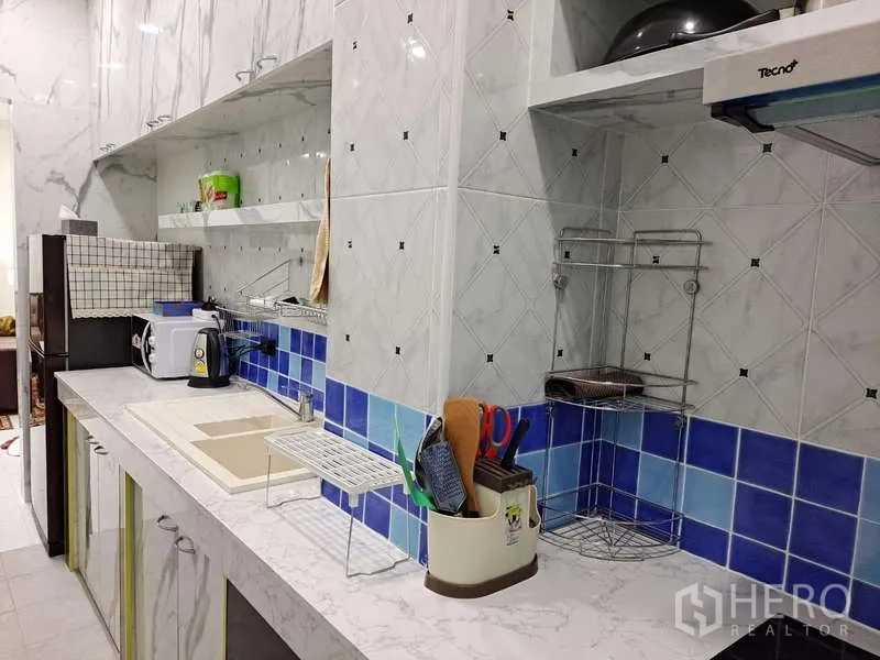 公寓 出租在Khlong Toei, Bangkok - 厨房沿墙布置收纳与电器，大理石台面配蓝色瓷砖。