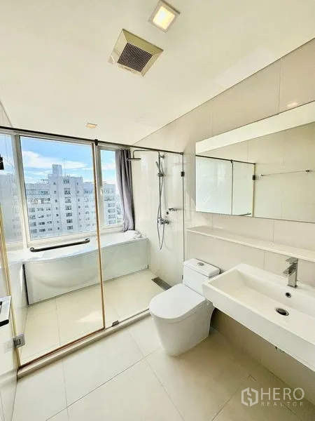 Condominium for rent in Watthana, Bangkok - Bright bathroom with bathtub by the window, glass shower, and vanity.