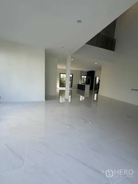 Detached House for rent in Bang Khen, Bangkok - Spacious living and dining zone with polished tiles, double-height ceiling and mezzanine-style railing.