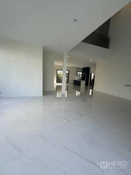 Detached House for rent in Bang Khen, Bangkok - Spacious living and dining zone with polished tiles, double-height ceiling and mezzanine-style railing.