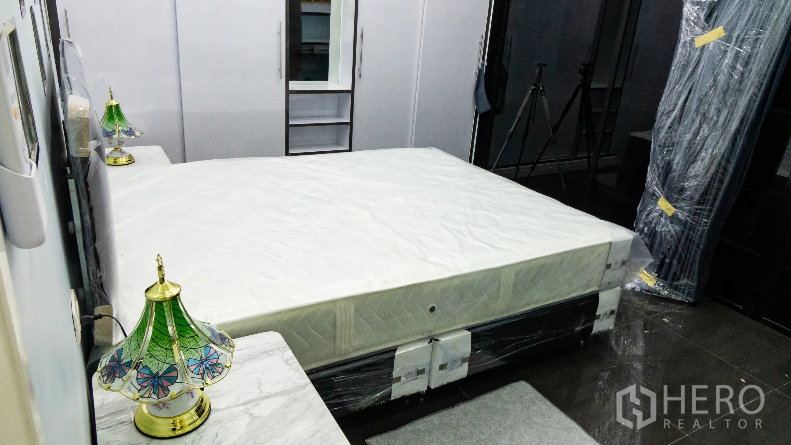 Condominium for rent or sale in Khlong Toei, Bangkok - Bedroom with large bed, glossy white wardrobes and a mirrored dressing area.