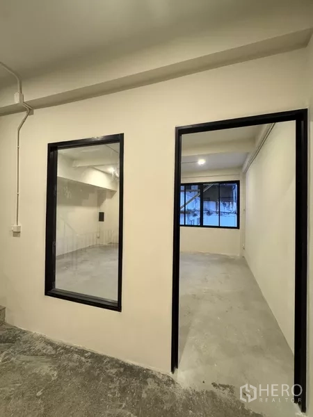 Shophouse for rent - Long open office floor with a large rear window and rows of ceiling lights.