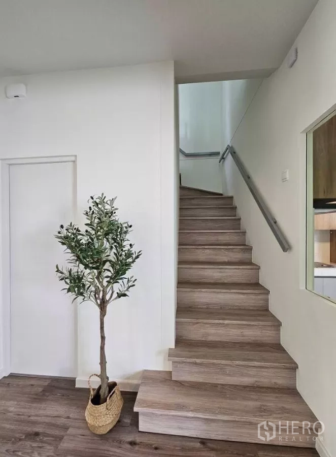 Detached House for rent in Bang Phli, Samut Prakan - Wood staircase with minimalist handrail and a decorative potted plant.