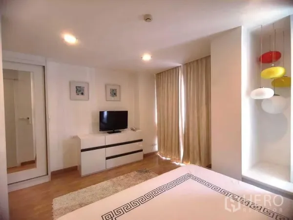 公寓 出租在Watthana, Bangkok - 温馨卧室，电视柜、遮光窗帘、柔和灯光与地毯。