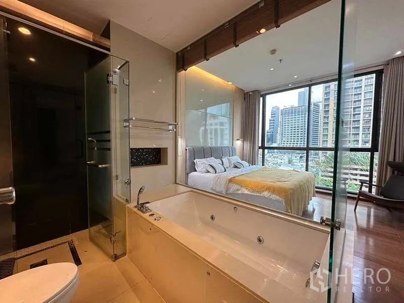 公寓 出租在Khlong Toei, Bangkok - 套内卫浴带大浴缸与玻璃淋浴间，可望向卧室与天际线。