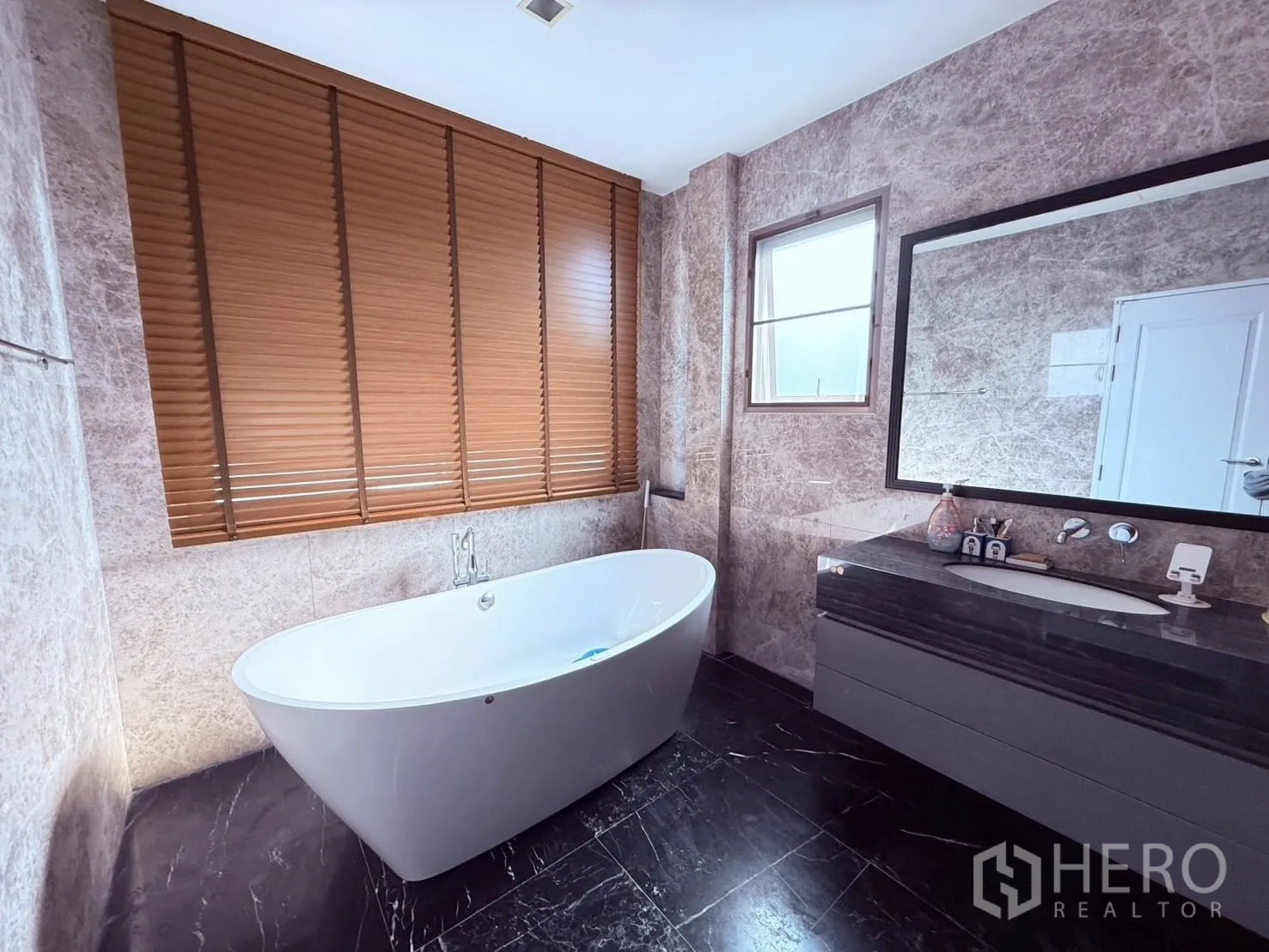 Detached House for rent or sale in Prawet, Bangkok - Luxurious bathroom with freestanding bathtub, stone-look walls, vanity, and window.