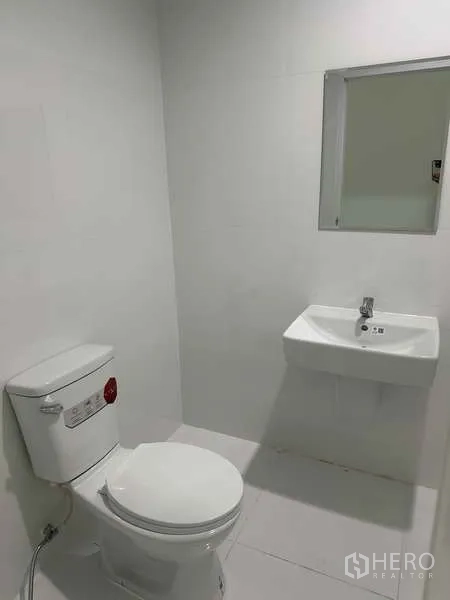 Factory for rent in Khlong Luang, Pathum Thani - Clean restroom with toilet, sink and mirror in white tile finish.