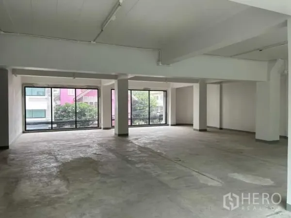 Office Space for rent in Bang Rak, Bangkok - Open-plan office floor with concrete finish and floor-to-ceiling glass windows.