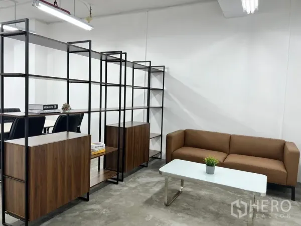办公空间 出租在Sathon, Bangkok - 休息角落设棕色沙发、白色茶几与金属置物架。