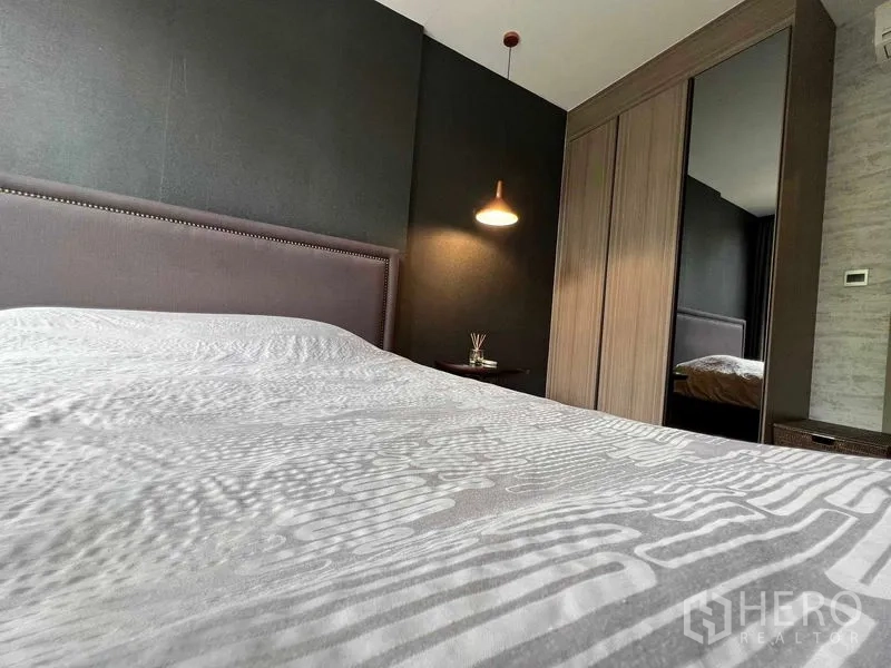公寓 出租在Watthana, Bangkok - 卧室一角，内置镜面衣柜与床侧吊灯。