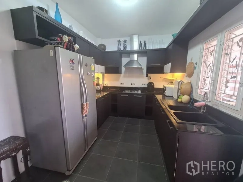 Detached House for rent in Sai Mai, Bangkok - U-shaped kitchen with dark cabinetry, stone countertops and stainless range hood.