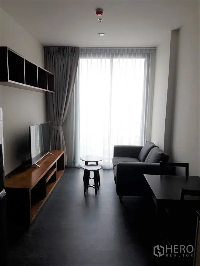 公寓 出租或出售在Watthana, Bangkok - 素坤逸公寓明亮客厅，配沙发、电视柜与落地窗和纱帘。