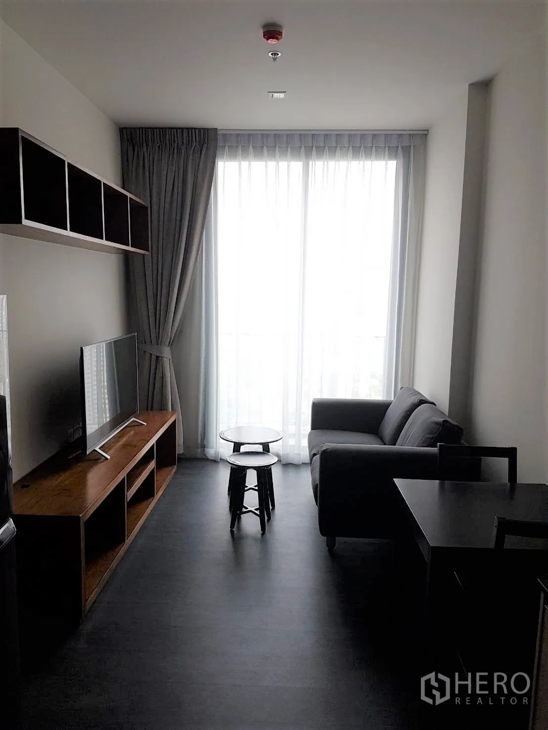 公寓 出租或出售在Watthana, Bangkok - 素坤逸公寓明亮客厅，配沙发、电视柜与落地窗和纱帘。