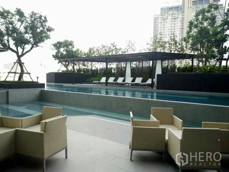 Condominium for rent or sale in Huai Khwang, Bangkok - Condo facilities featuring outdoor swimming pool, sun loungers and seating area.
