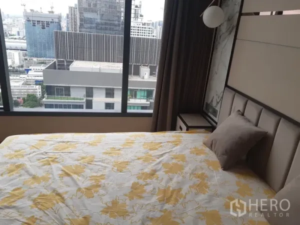 公寓 出租或出售在Watthana, Bangkok - 卧室配软包床与床头柜，窗外城市景观。