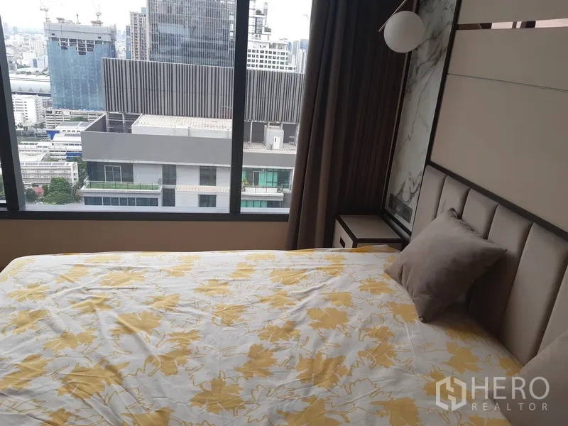 公寓 出租或出售在Watthana, Bangkok - 卧室配软包床与床头柜，窗外城市景观。