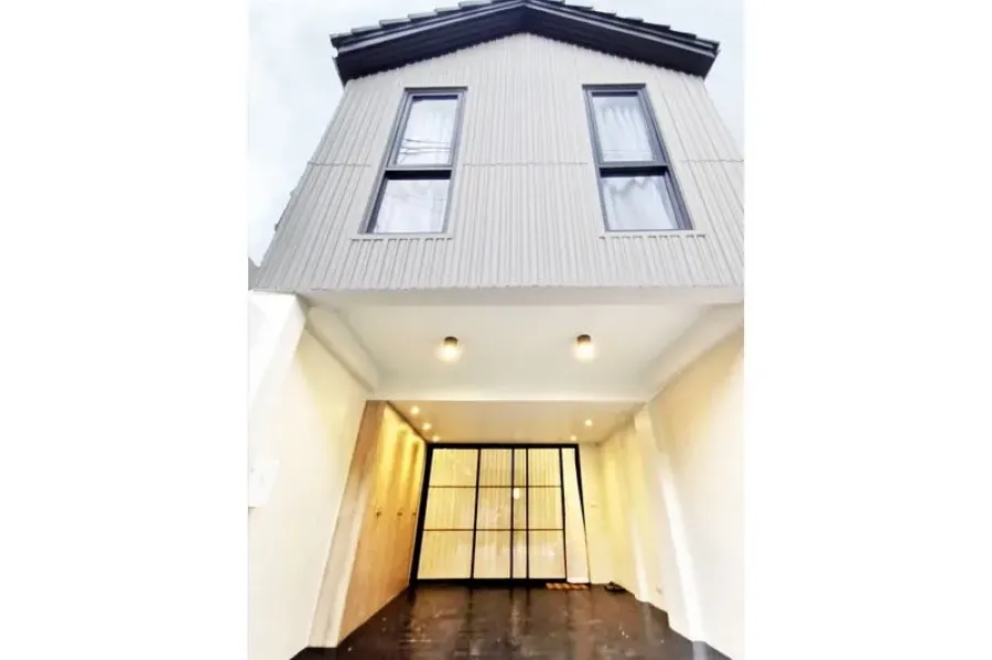 Townhouse for rent in Khlong Toei, Bangkok - Modern two-storey townhouse facade with gable roof, twin vertical windows and a covered carport.