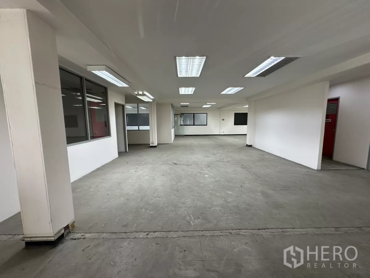 Warehouse for rent in Suan Luang, Bangkok - Large open-plan office floor with white columns, smooth concrete floor, and overhead fluorescent lights.