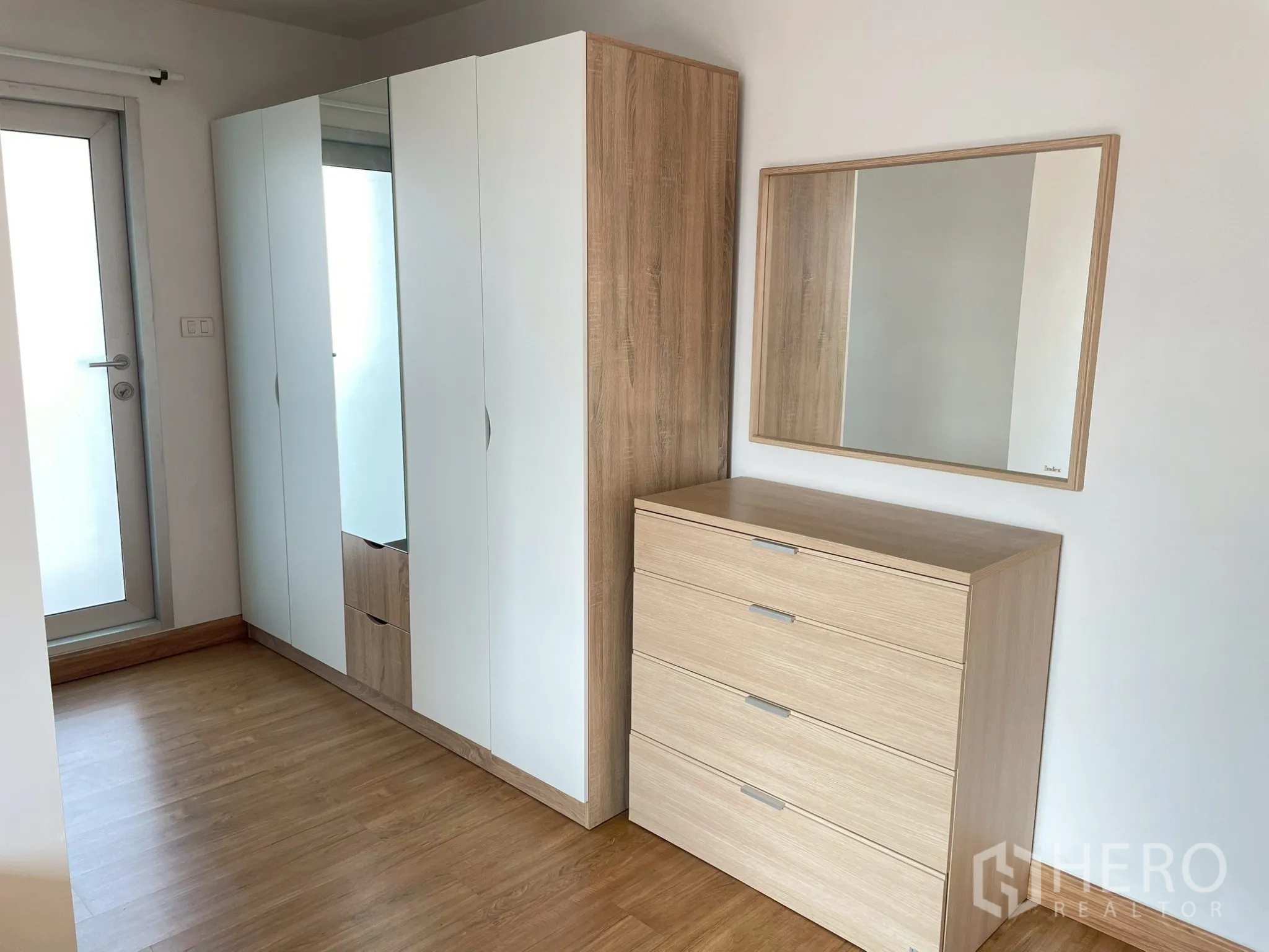 อพาร์ทเมนท์ for rent in Khlong Toei, Bangkok - มุมห้องนอนมีตู้เสื้อผ้าสีขาว ตู้ลิ้นชัก และกระจกเงา พื้นไม้