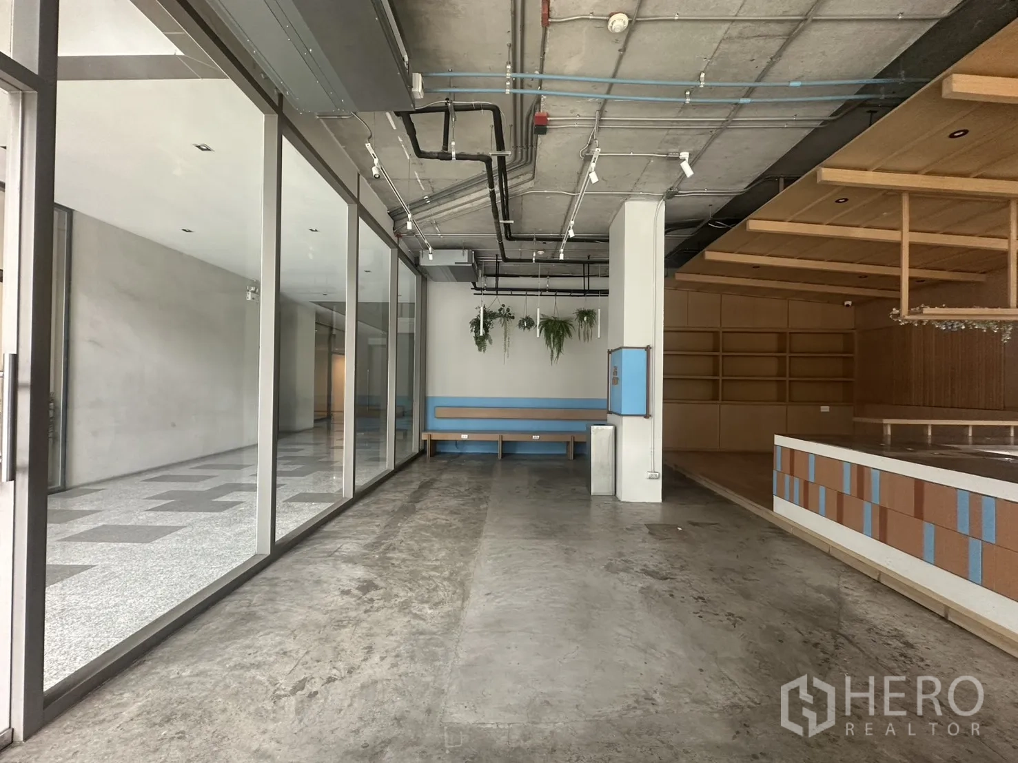 Retail Space for rent - Spacious retail unit with glass partition, wood shelving, and suspended lighting rails.