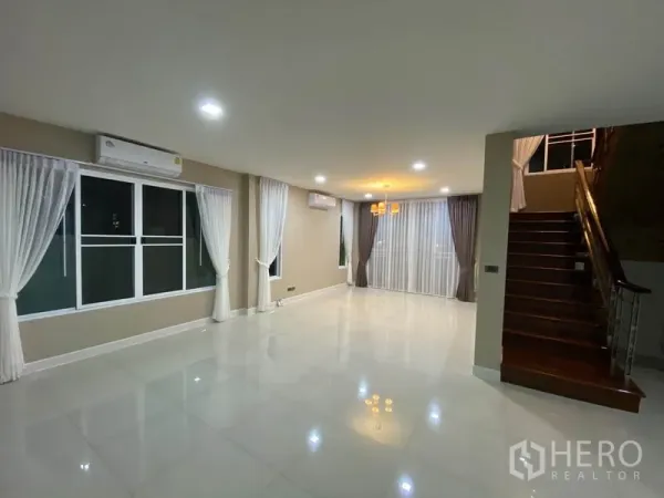 独立式住宅 出租在Prawet, Bangkok - 开放式客餐厅，吊灯点缀，采光良好，旁为木质楼梯。