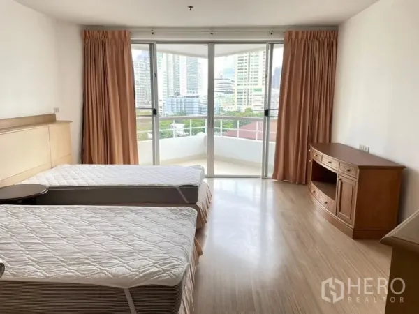 Condominium for rent in Khlong Toei, Bangkok - Bright bedroom with two single beds and floor‑to‑ceiling doors opening to a balcony city view.