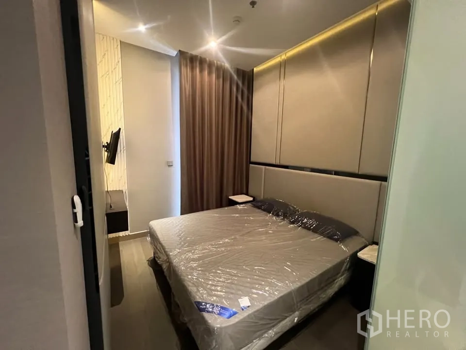 公寓 出租在Huai Khwang, Bangkok - 温馨卧室，遮光窗帘、软包背景墙与床侧置物架。