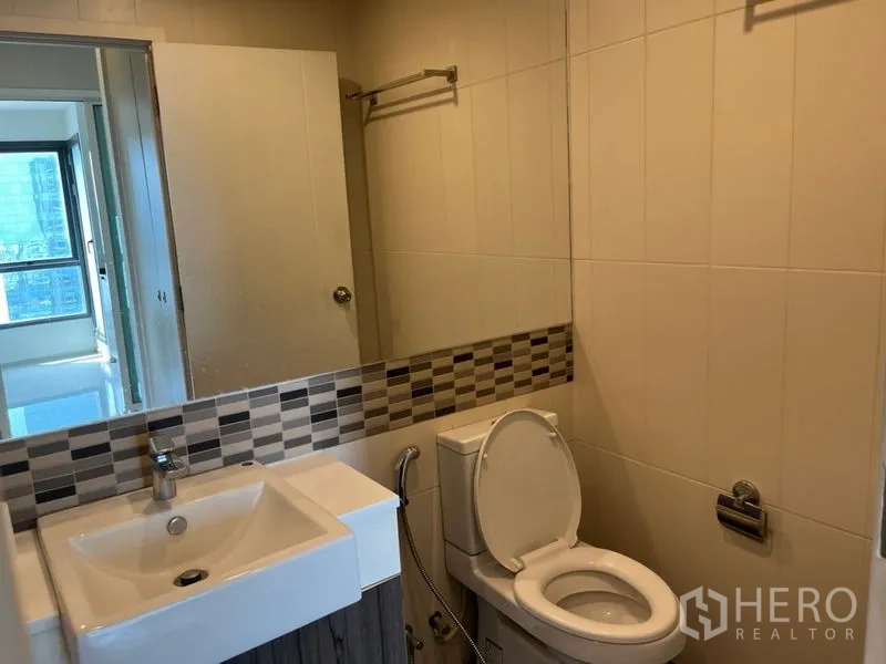Condominium for sale in Phaya Thai, Bangkok - Bright tiled bathroom with vanity, mirror and toilet in a Phaya Thai condo.