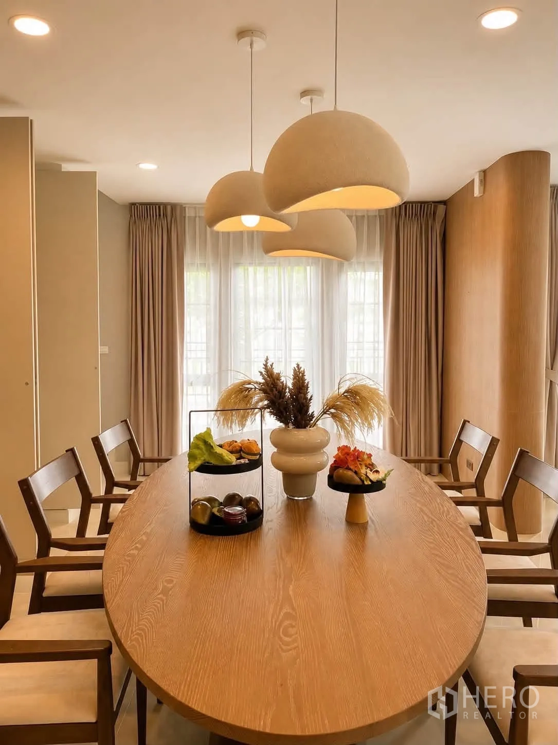Detached House for rent in Bang Phli, Samut Prakan - Dining room with an oval wooden table, pendant lights and sheer curtains.