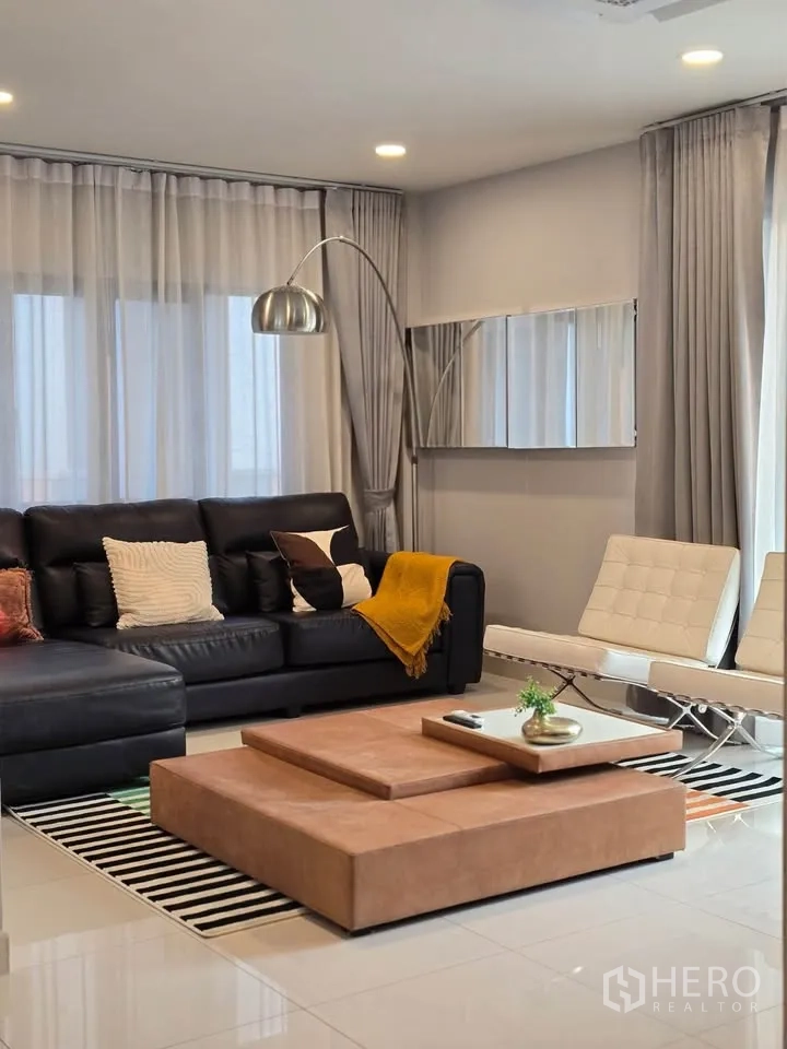 Detached House for rent or sale in Bang Phli, Samut Prakan - Lounge with large sectional sofa and low coffee table on a striped rug.