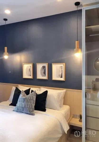 Condominium for rent in Watthana, Bangkok - Bedroom with pendant bedside lights, framed artwork, and a built-in closet against a blue wall.