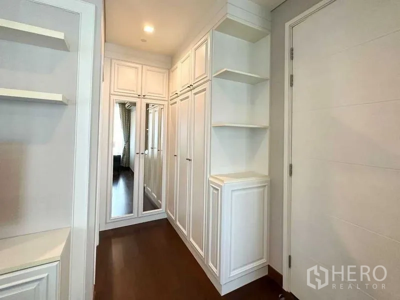 Condominium for rent in Watthana, Bangkok - Walk-in closet with white built-in wardrobes and mirrored doors.