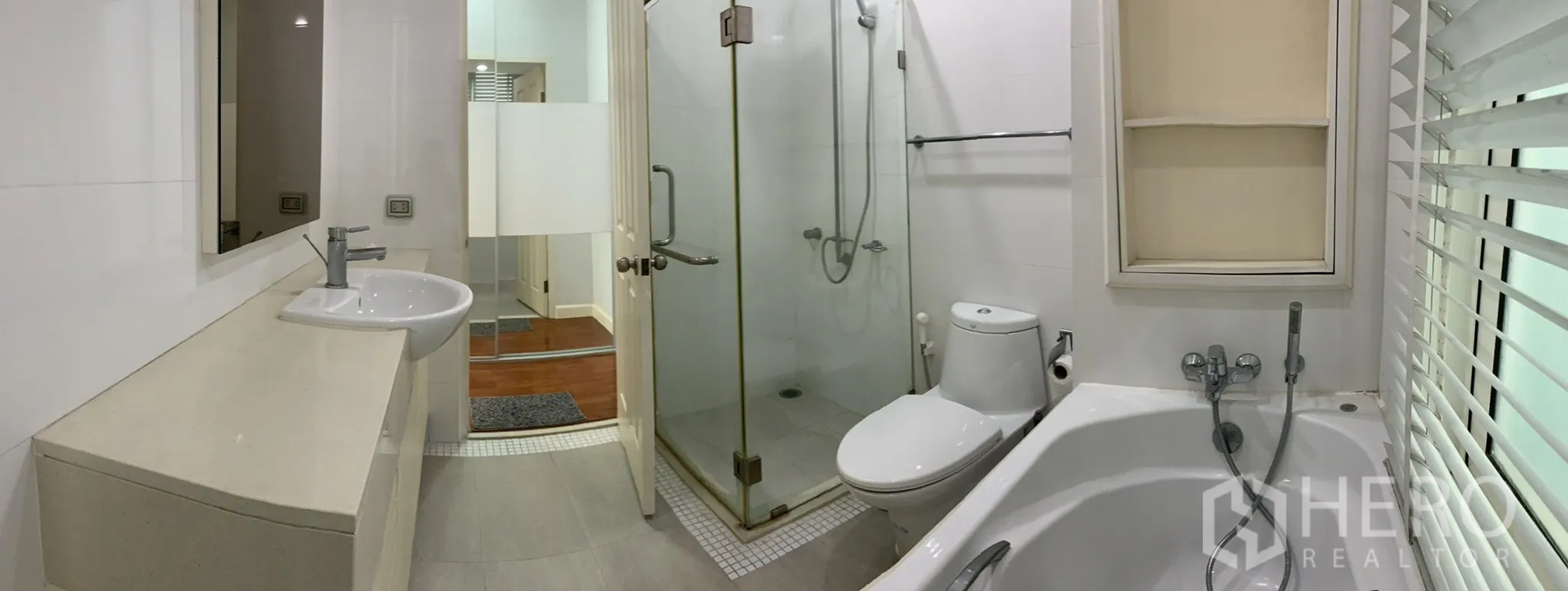 Condominium for rent in Khlong Toei, Bangkok - Spacious bathroom featuring a glass shower enclosure, toilet, built-in shelves and bathtub.