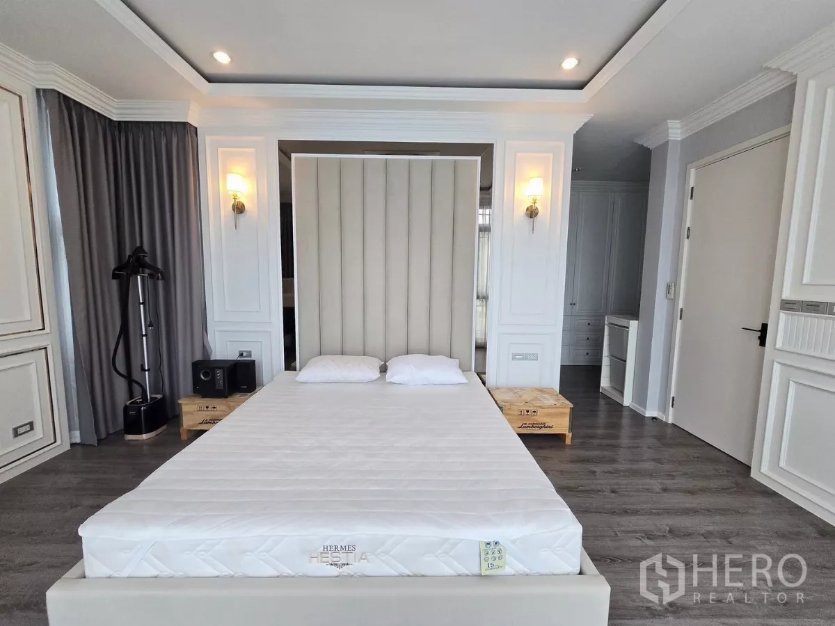 独立式住宅 出租在Prawet, Bangkok - 主卧设高背软包床头、木地板与壁灯。
