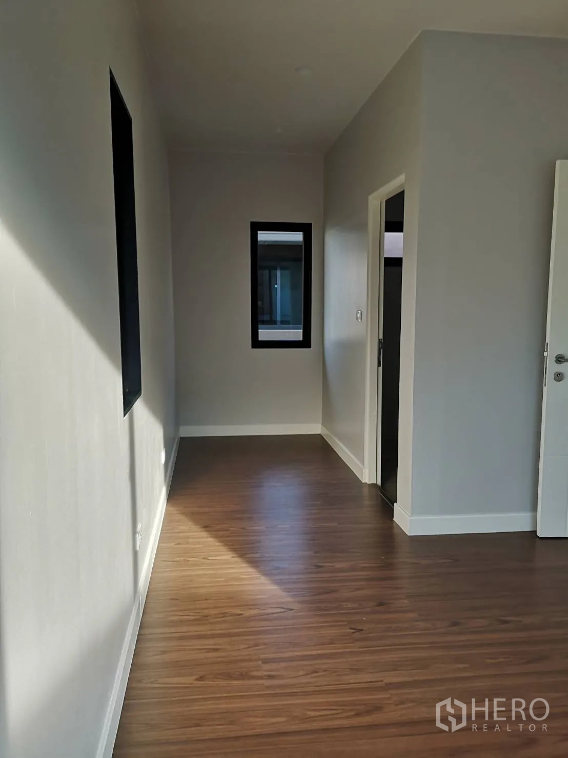 Detached House for sale in Lam Luk Ka, Pathum Thani - Upper hallway with wood-look floors and a black-framed window leading to bedrooms.