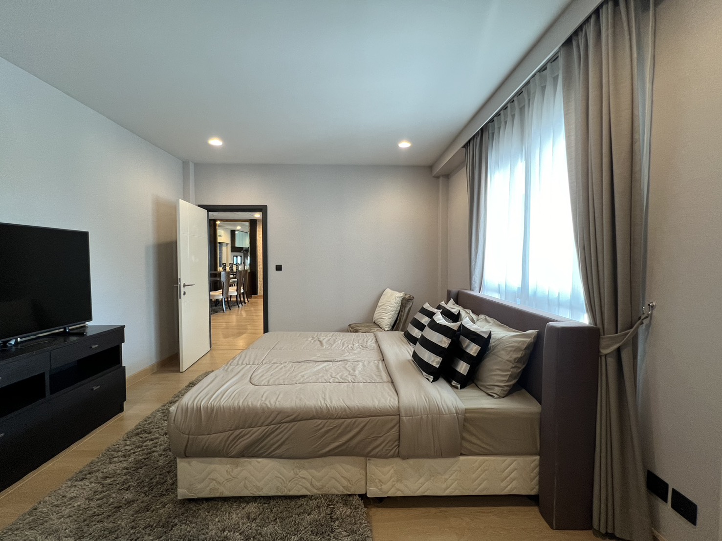 Detached House for rent in Bang Kapi, Bangkok - Guest bedroom with large window, neutral decor and wall-mounted TV.