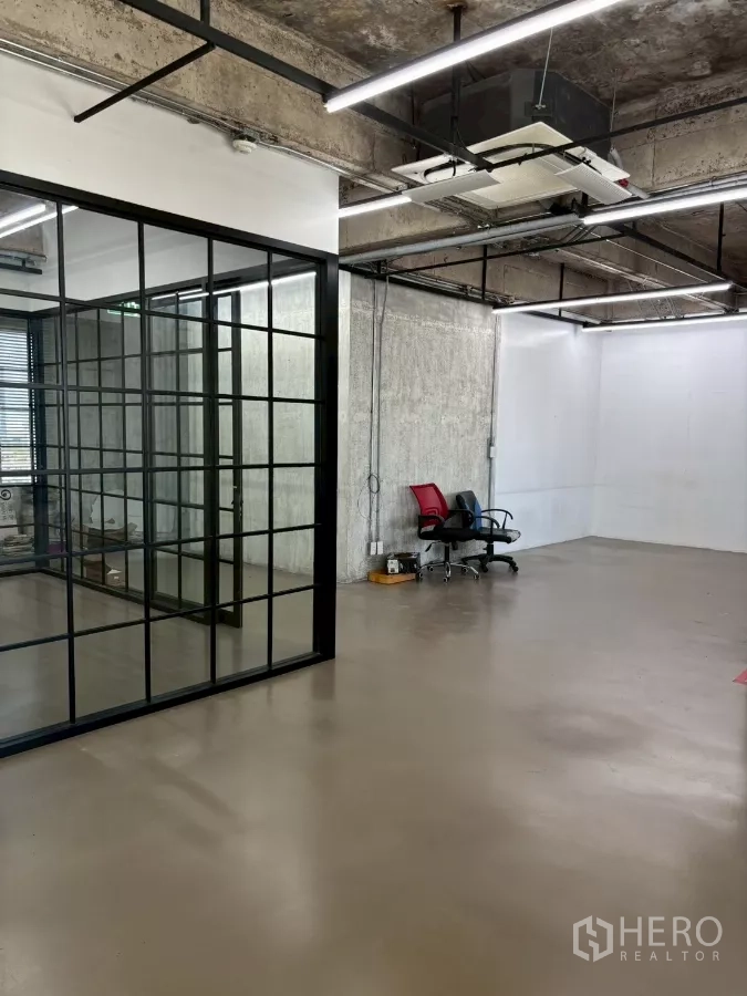 办公空间 出租在Watthana, Bangkok - 玻璃隔断旁的开放区域，外露混凝土天花与嵌入式空调。