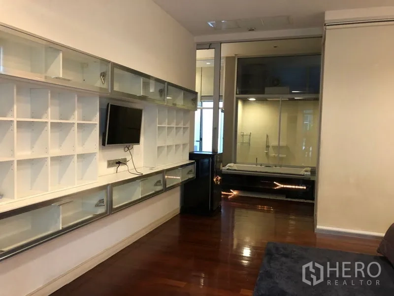 Townhouse for rent or sale in Chatuchak, Bangkok - Family room with long display shelving and a glass-walled bathroom beyond.
