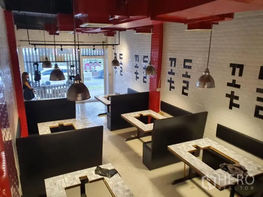 Shophouse for rent in Khlong Toei, Bangkok - Restaurant-style shophouse interior with booth seating, pendant lights, white subway tile walls and red exposed ceiling ducts.